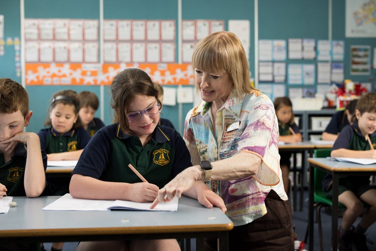 teacher-helping-student-at-desk-with-writing