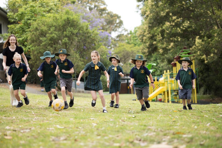 students-in-playground-chasing-after-ball-with-teacher-following