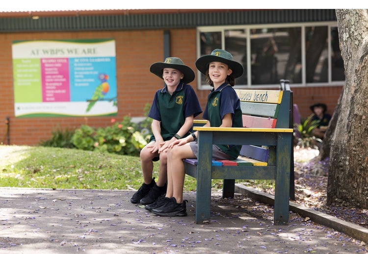 two-students-sitting-on-buddy-bench